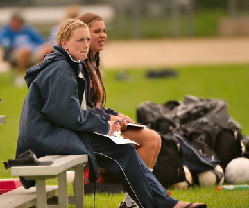 Tori Hebner and Emma Comiskey sit on the bench as they watch their team play against Natick at home on 