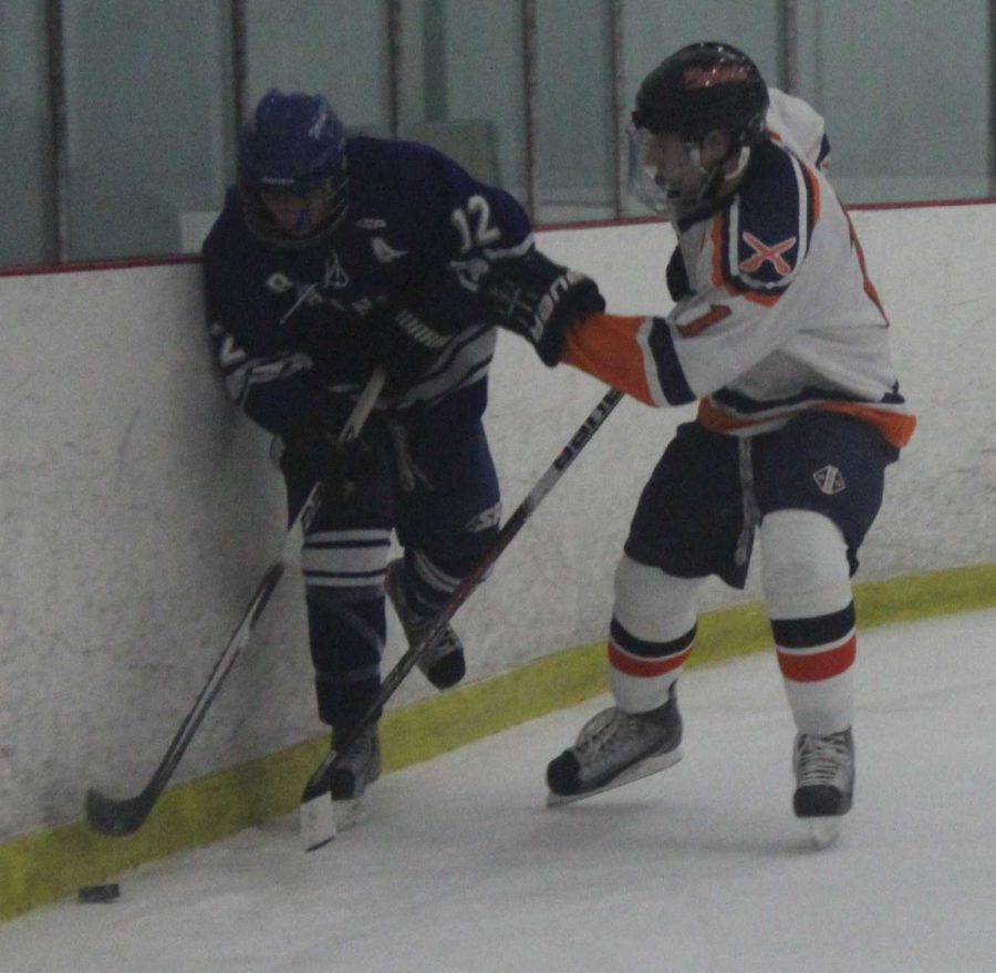 The junior Captain of the boys hockey team battles a Braintree player for the puck along the boards. (Photo/Jennifer Harrop)