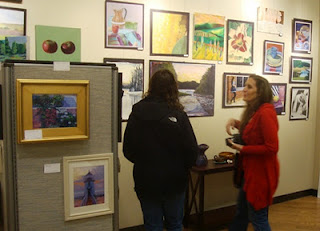 Teacher Ms. Allison views the art alongside a student