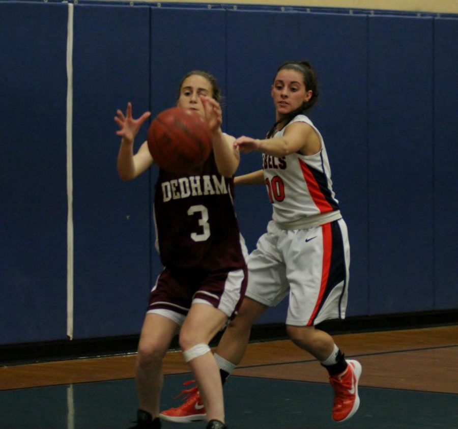 A Walpole player defenses a Dedham guard in the paint.