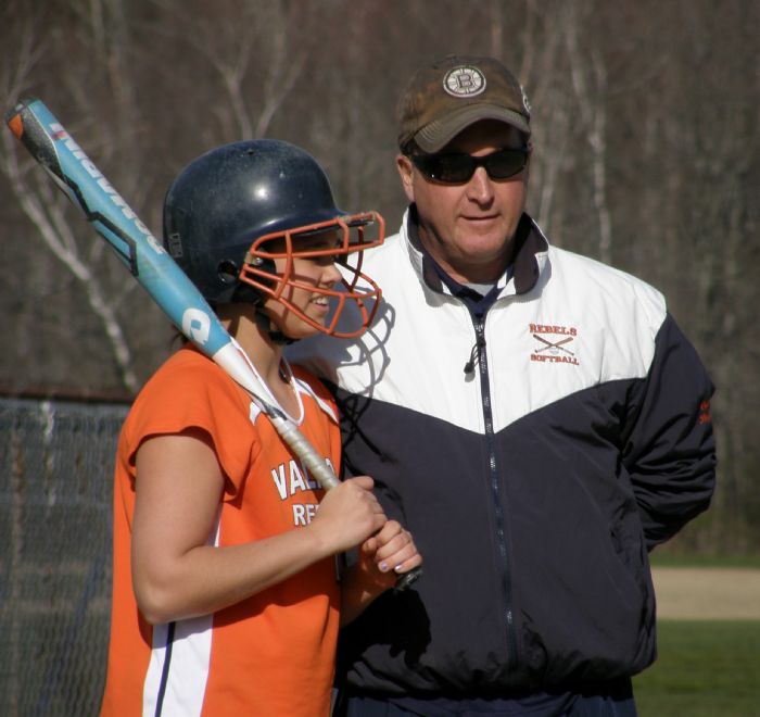 Walpole coach talks to his player before she gets up to bat.