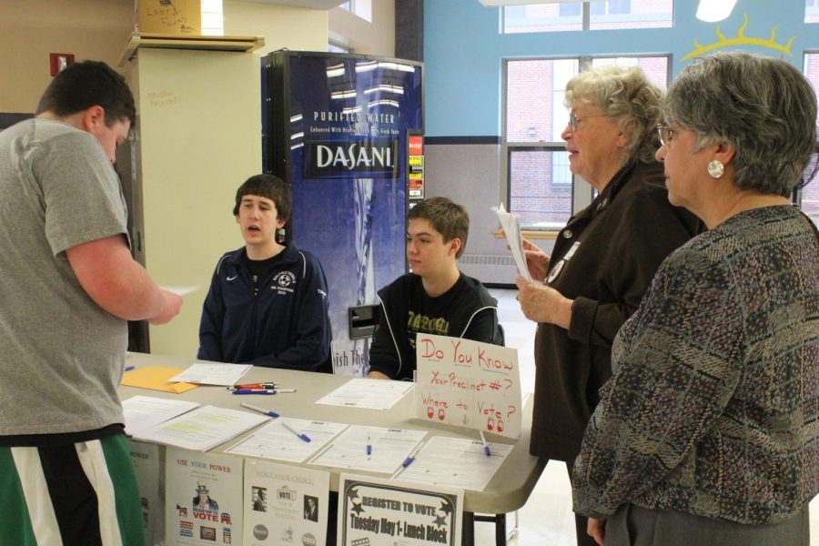 Some women involved in the League of Women Voters converse with a student registering to vote.