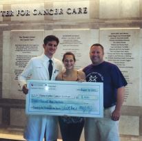 Dr. Wolpin, head of research team, pose with her and her father as they donate the money they raised.