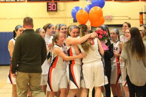 Walpole Alum Summer King being congratulated by her teammates and coach for surpassing the 1000 points mark in basketball.