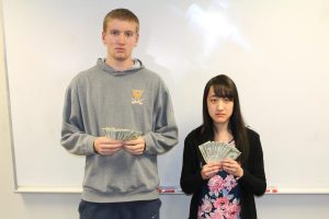 The "most likely to succeed" winners jokingly flaunt money while taking their superlative photo.