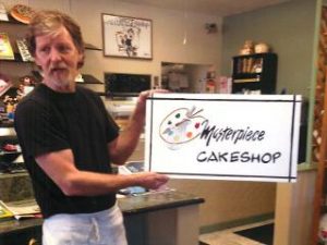 Jack Phillips, owner of Masterpiece Cake Shop and discrimination victim, poses with a sign for his shop (www.barbwire.com - image credit rossrighttriangle.wordpress.com).