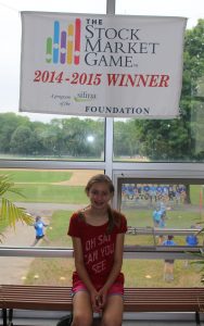 This sixth grade winner sits under her "Stock Market Game 2014-2015" banner on June 15 at Bird Middle School (Photo/Melanie Weber).