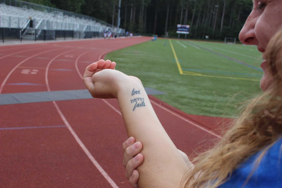 Kyra Arsenault shows off her tattoo, Love never fails, at cross country practice on September 29 (Photo/ Delaney Murphy).