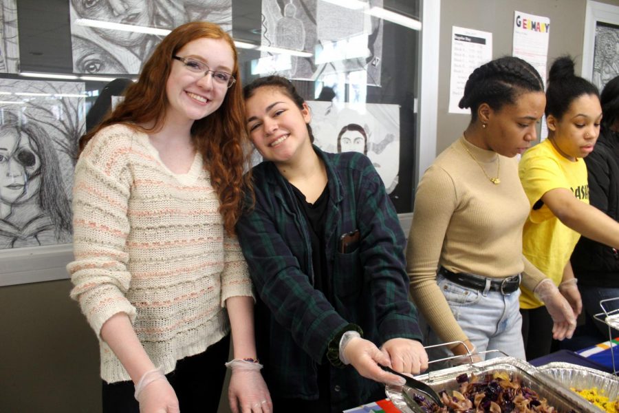 Juniors and Feminism Club members Aislyn O'Connell and Ava Jingozian serve food together.