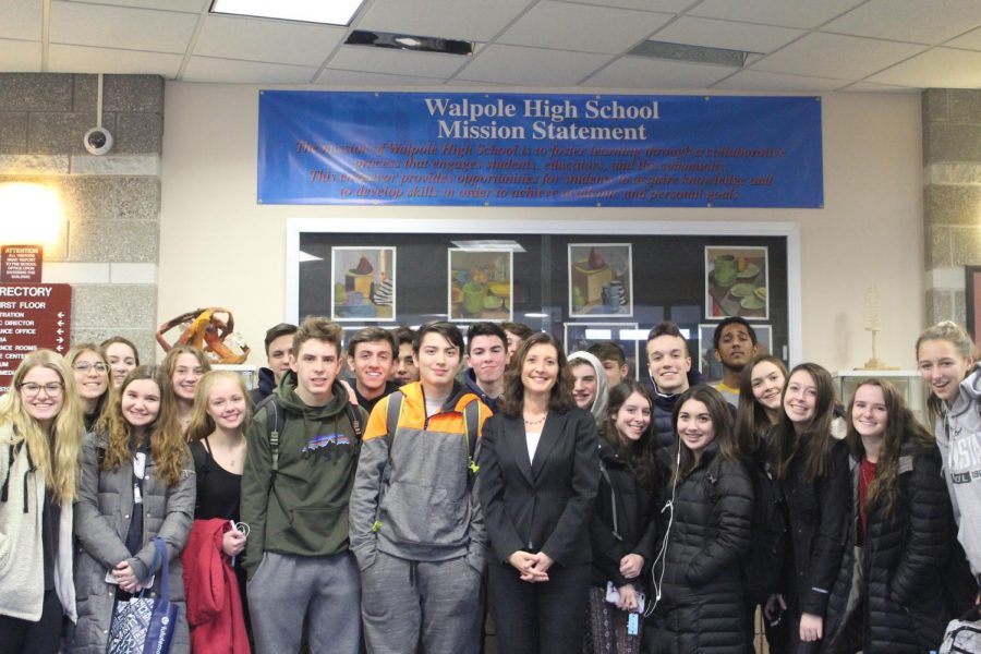 Dr. Bridget Gough stands with students in the Walpole High main lobby under the school mission statement.