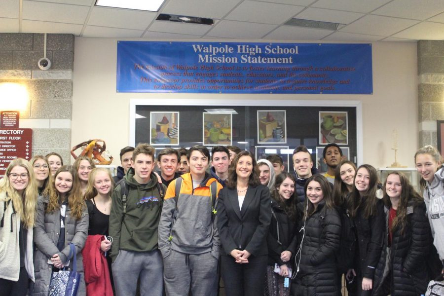 Dr.+Bridget+Gough+stands+with+students+in+the+Walpole+High+main+lobby+under+the+school+mission+statement.