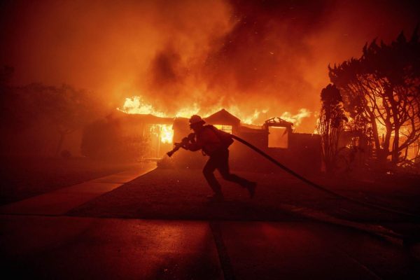 A firefighter battles the Palisades Fire as it burns a structure in the Pacific Palisades neighborhood of Los Angeles, Tuesday, Jan. 7, 2025. 